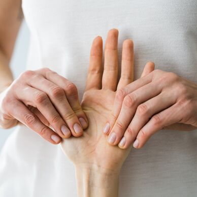 Therapiesituation: Therapeutin behandelt Hand eines Patienten